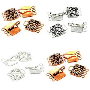 May include: An assortment of jewelry clasps in copper, silver, and gold tones. The clasps feature a decorative square design with an ornate pattern and multiple loops for attaching to jewelry pieces. The clasps are shown in various arrangements.