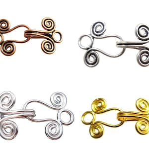 May include: Four metal clasps in different finishes: copper, silver, nickel, and gold. Each clasp has a unique design with two swirls on each side.