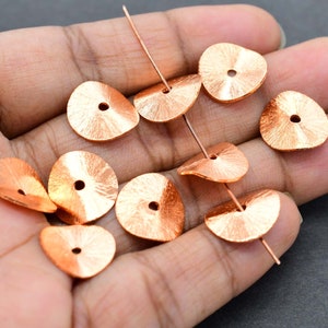 May include: Copper-coloured, textured metal beads with a central hole. The beads are teardrop-shaped and strung on copper wire. Suitable for jewellery making and crafting projects.