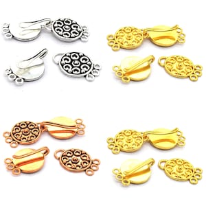 Peut inclure: Une collection de fermoirs à bijoux multi-brins dans des tons argent, or et cuivre. Chaque fermoir présente une plaque décorative circulaire avec un motif en relief et trois petites boucles de chaque côté pour attacher des fils ou chaînes.