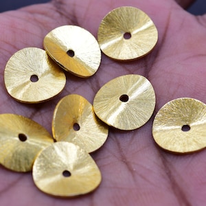 May include: Eight gold-coloured metal discs with a hole in the centre. The discs have a textured, slightly raised surface.