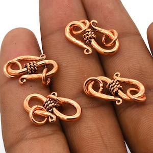 Pode incluir: Quatro fechos de metal de cor cobre com um design de fio torcido. Os fechos são projetados para serem usados na fabricação de joias.