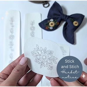 Könnte beinhalten: Stick- und Stickzubehör mit floralen Designs. Enthält eine marineblaue Schleife mit gestickten Sonnenblumen, Stoffflicken mit floralen Mustern und den Text "Stick and Stich Herbstmotive."