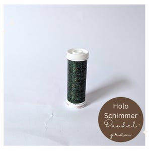 Könnte beinhalten: Eine Spule mit dunkelgrünem holografischem Schimmergarn. Das Etikett lautet "Holo Schimmer Dunkel-grün".