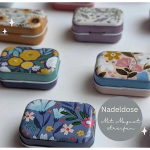 Könnte beinhalten: Mehrere rechteckige Metalldosen mit floralen Designs. Die Dosen haben verschiedene Farbschemata, darunter Gelb, Blau, Rosa und Lila. Der Text "Nadelose Mit Magnetstreifen" ist sichtbar.