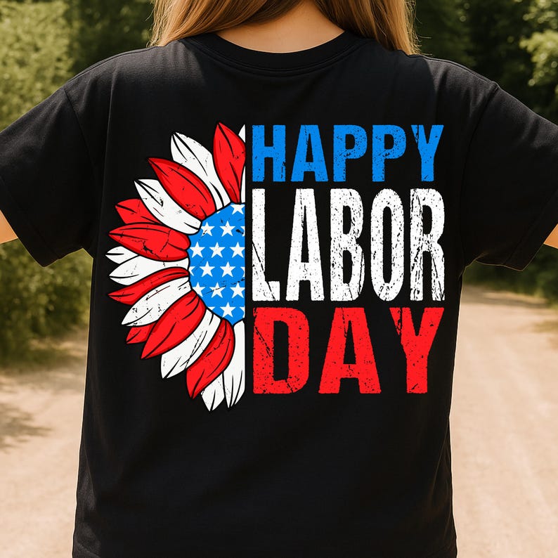 Pode incluir: Camiseta preta com um design patri&oacute;tico de girassol. A flor tem p&eacute;talas vermelhas, brancas e azuis e um centro azul com estrelas brancas. As palavras "HAPPY LABOR DAY" s&atilde;o impressas em branco, azul e vermelho.