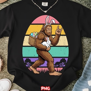 May include: Black sweatshirt featuring a Bigfoot character wearing bunny ears, carrying a basket of Easter eggs and a white rabbit. The design includes a colorful egg-shaped background with a retro vibe. The text "PNG" is at the bottom.