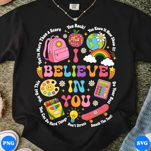 Peut inclure: Sweat-shirt noir avec un graphisme coloré disant "I Believe in You". Le motif comprend un sac à dos rose, un arc-en-ciel, un globe, un skateboard et d'autres illustrations sur le thème de l'école. Le texte comprend également des phrases comme "You Rock!" et "Smash the Test!"