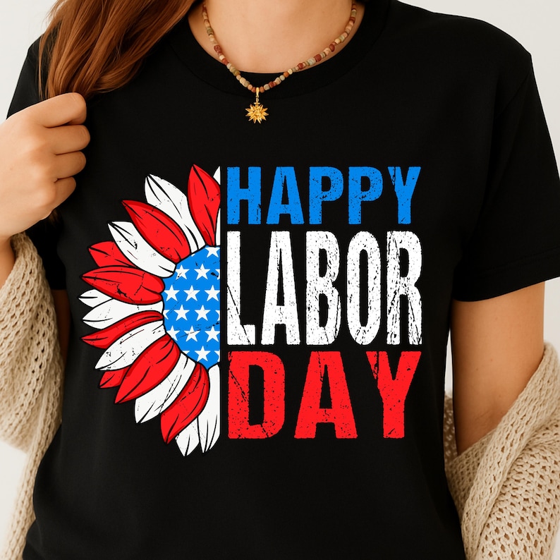 Pode incluir: Camiseta preta com um design patri&oacute;tico de girassol. O girassol tem p&eacute;talas vermelhas, brancas e azuis e um centro azul com estrelas brancas. O texto "HAPPY LABOR DAY" est&aacute; em azul, branco e vermelho.