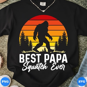 Può includere: Felpa nera con una silhouette di Bigfoot che cammina davanti a un tramonto. Il testo "BEST PAPA Squatch Ever" è stampato in bianco. Il design include alberi ed erba.