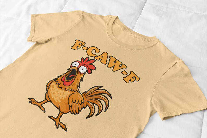 May include: A light tan t-shirt featuring a cartoon chicken with a surprised expression and open beak. The text "F-CAW-F" is printed above the chicken in orange letters. The chicken is brown, orange, and red.