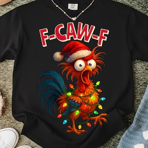 Puede incluir: Sudadera negra con un gallo de dibujos animados con gorro de Papá Noel y luces navideñas. El texto rojo "F-CAW-F" está impreso encima del gallo. La sudadera es de un material suave.