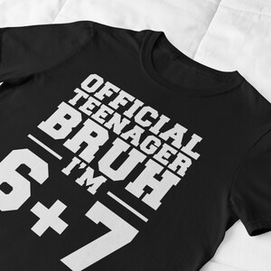 May include: Black t-shirt with the text "OFFICIAL TEENAGER BRUH I'M 6+7" in white, bold, block letters. The shirt is made of a soft material and is suitable for casual wear.