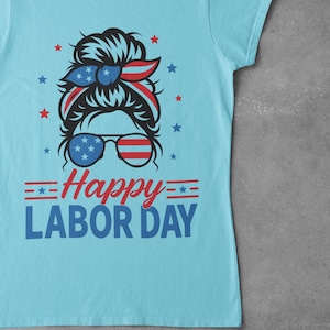 May include: Light blue t-shirt with a graphic design for Labor Day. The design features a woman's face with sunglasses and a headband in red, white, and blue, along with the text "Happy Labor Day."