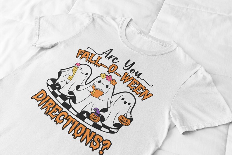 K&ouml;nnte beinhalten: Wei&szlig;es T-Shirt mit einem Halloween-Motiv. Das Design zeigt drei Cartoon-Geister mit Accessoires, ein Schachbrettmuster und den Text "Are You Fall-O-Ween Directions?" in Orange und Schwarz.