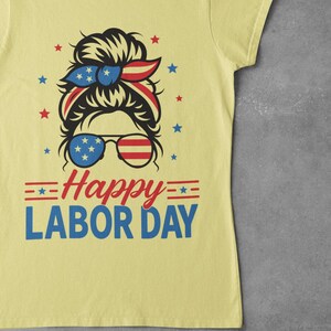 May include: Yellow t-shirt with a graphic design for Labor Day. The design features a woman's face with sunglasses and a headband in red, white, and blue. The text "Happy Labor Day" is below the face.