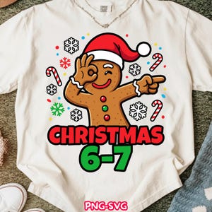 Peut inclure: T-shirt crème avec un bonhomme en pain d'épices portant un bonnet de Père Noël, faisant le geste « OK ». Le motif comprend le texte « CHRISTMAS 6-7 » en rouge et vert, des flocons de neige et des cannes en sucre. Le bas du t-shirt indique « PNG-SVG ».