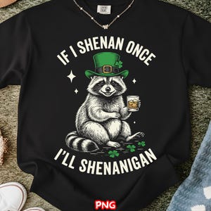 以下が含まれることがあります： 黒いTシャツ。緑のセントパトリックデーの帽子をかぶったアライグマが飲み物を持っています。「If I Shenan Once, I'll Shenanigan」と書かれています。デザインにはクローバーと星が含まれています。