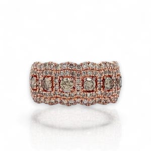 May include: A rose gold band ring featuring a central row of five larger round-cut champagne-colored diamonds, bordered by multiple rows of smaller pavé-set white diamonds that create a wide, textured, and sparkling surface.