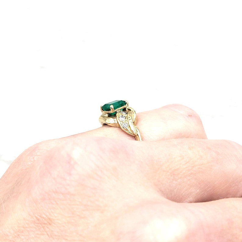Vintage Emerald Ring in 14k Yellow Gold with Diamonds. Lucious medium Green Emerald cut Emerald makes a Statement in an Art Nouveau-esque Setting. Not too big or too small this half-carat size gemstone is a beautiful sample of Natural Emerald sure to Complement any Outfit.