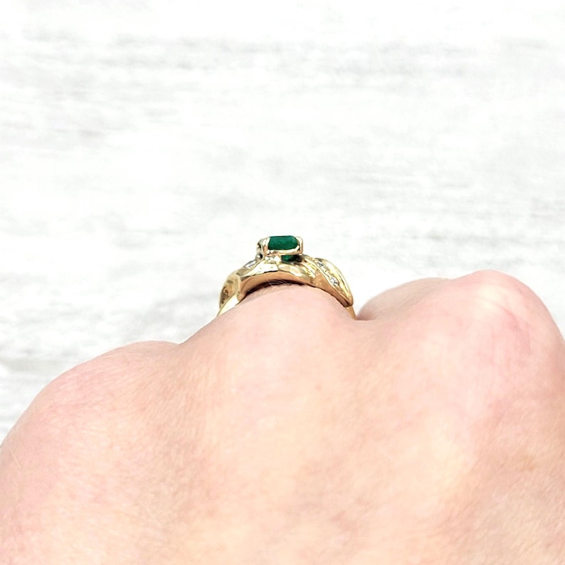 Vintage Emerald Ring in 14k Yellow Gold with Diamonds. Lucious medium Green Emerald cut Emerald makes a Statement in an Art Nouveau-esque Setting. Not too big or too small this half-carat size gemstone is a beautiful sample of Natural Emerald sure to Complement any Outfit.