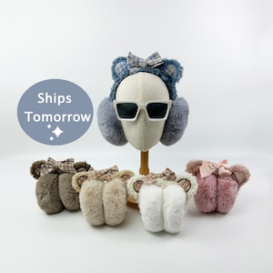 Puede incluir: Cuatro pares de orejeras de piel sintética con orejas de oso y lazos a cuadros. Las orejeras son de color marrón, beige, blanco y rosa.