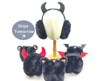 May include: Four pairs of black faux fur earmuffs with different animal ear accents. One pair has black devil horns, one pair has red devil horns, one pair has black cat ears, and one pair has black bat wings.