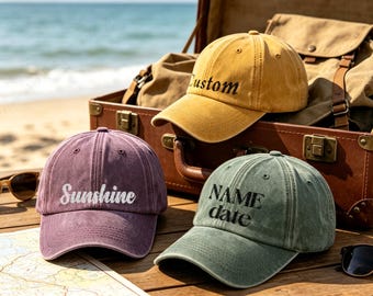 May include: Three baseball caps in mustard yellow, dusty purple, and sage green. The yellow cap features the word Custom, the purple cap features the word Sunshine, and the green cap features the words NAME date embroidered in black or white thread.