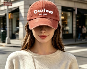 May include: A rust-colored baseball cap with a curved brim and a six-panel construction. The front of the cap features the white text "Custom" in a bold, rounded font, with the smaller white text "Est 2026" positioned directly underneath.