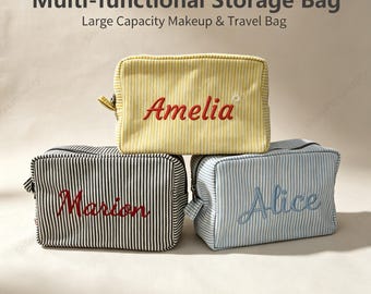 May include: Three rectangular storage bags with zippers, featuring vertical stripes in yellow, black, and light blue. Each bag is embroidered with a name: Amelia in red, Marion in red, and Alice in blue. Text reads Multi-functional Storage Bag.