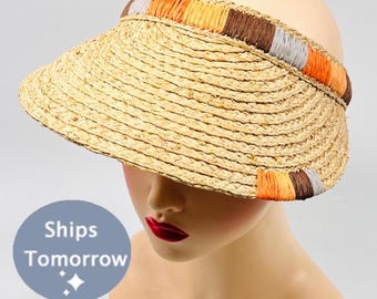 May include: A straw sun visor with a wide brim and a colorful braided trim in shades of orange, brown, and gray.
