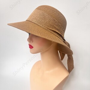 May include: A brown straw sun hat with a wide brim and a tied bow at the back.