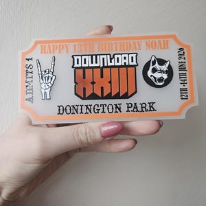 May include: A personalised ticket with an orange border. Text includes "HAPPY 13TH BIRTHDAY NOAH", "DOWNLOAD", and "DONINGTON PARK". The dates "12TH-14TH JUNE 2026" are also displayed. A skeleton hand giving the rock on sign is on the left.