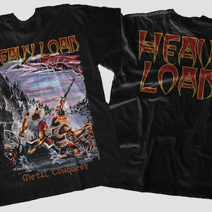 Könnte beinhalten: Schwarzes T-Shirt mit einem goldenen und roten "Heavy Load"-Logo auf Vorder- und Rückseite. Das Design auf der Vorderseite zeigt eine Fantasy-Szene mit zwei Kriegern und dem Text "Metal Conquest".