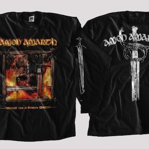 May include: Black long-sleeve shirt featuring the band name "Amon Amarth" in white on the sleeves and the front and back. The front design includes a sword and a fiery background. The back features a sword design.