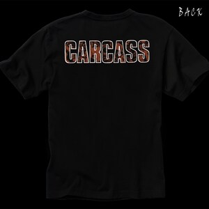 Może przedstawiać: Czarny T-shirt z nadrukiem słowa "CARCASS" białymi literami na plecach. Litery są obwiedzione brązowym kolorem.