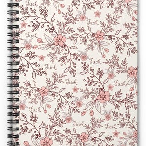 May include: Spiral-bound notebook with a floral pattern in pink and brown on an off-white background. The word "Fuck" is repeated throughout the design. The notebook has a black spiral binding.