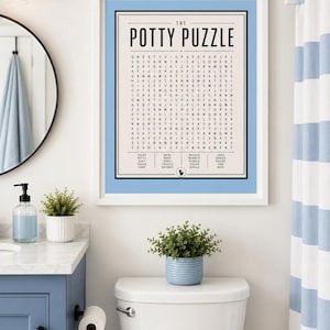 K&ouml;nnte beinhalten: Ein gerahmter Wandkunstdruck mit dem Titel The Potty Puzzle, der ein Wortsuchr&auml;tsel mit schwarzem Text auf cremefarbenem Hintergrund zeigt, umrandet von einem hellblauen Rahmen. Der Druck enth&auml;lt eine Wortliste unten und ein kleines schwarzes WC-Symbol.