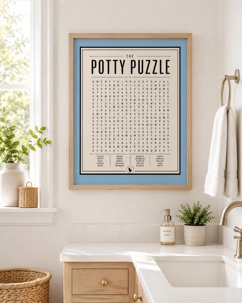 K&ouml;nnte beinhalten: Ein gerahmter Wandkunstdruck mit dem Titel The Potty Puzzle, der ein Wortsuchr&auml;tsel auf cremefarbenem Hintergrund mit einem hellblauen Rand zeigt. Das Gitter enth&auml;lt verschiedene W&ouml;rter rund ums Bad, die unten aufgelistet sind, wie toilet, seat und bath.