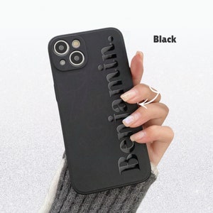 May include: Black phone case with the name "Benjamin" embossed vertically. The case has a matte finish and a camera cutout. The word "Black" is printed in the upper right corner.