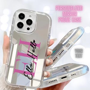 May include: A clear phone case with a mirror back. The case has a pink and black personalized design with the name "Ella Hall" on it. The case is designed to fit an iPhone.
