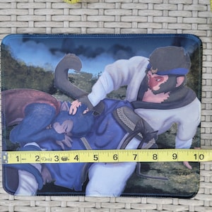 Puede incluir: Alfombrilla de ratón rectangular con una colorida ilustración de dos personajes antropomórficos con forma de mono en un entorno forestal. La alfombrilla mide aproximadamente 25 cm de largo y 18 cm de ancho.