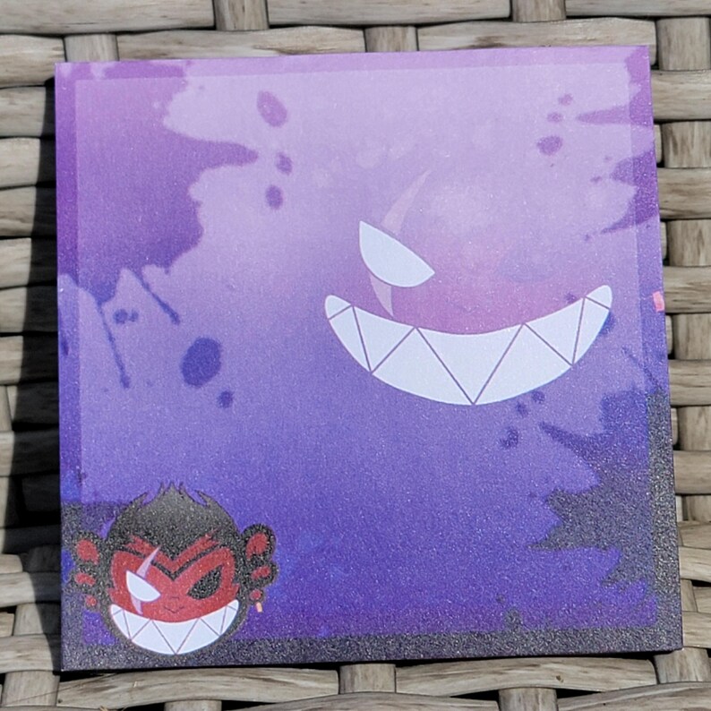 Puede incluir: Adhesivo cuadrado con fondo morado y negro con un fantasma de dientes blancos y un mono de cara roja con un pendiente rojo. El adhesivo tiene una textura brillante.
