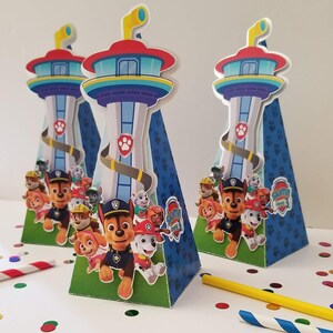 Puede incluir: Tres contenedores de fiesta en forma de cono azul y verde con tem&aacute;tica de Patrulla Canina. Cada contenedor presenta un personaje de Patrulla Canina, incluidos Chase, Skye y Marshall. Los contenedores est&aacute;n decorados con un logotipo de Patrulla Canina y una torre azul y blanca.