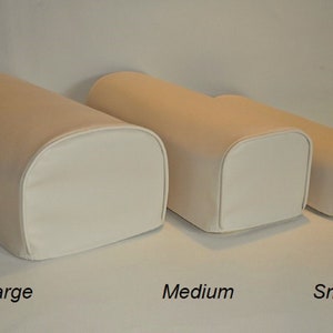 May include: Three beige and white cylindrical pillows in varying sizes: large, medium, and small. The pillows have rounded ends with white fabric and beige tops. Text labels indicate the size of each pillow.