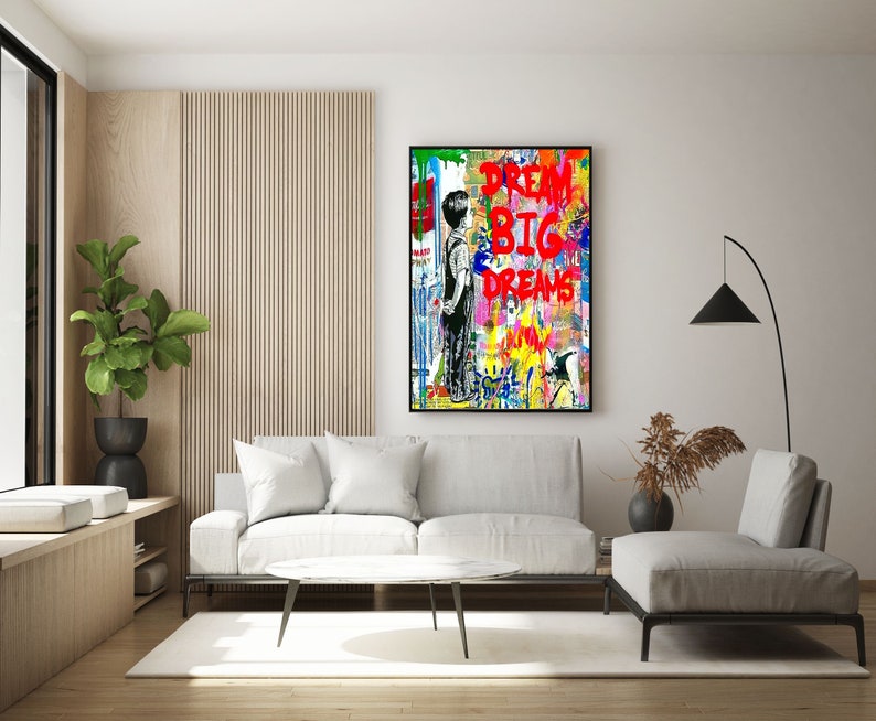 K&ouml;nnte beinhalten: Ein farbenfroher abstrakter Kunstdruck mit einer jungen Person, die vor einer Wand mit den Worten "Dream Big Dreams" in roter Farbe steht.