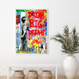 K&ouml;nnte beinhalten: Ein farbenfroher abstrakter Kunstdruck mit einem jungen Jungen, der vor einer Wand steht, auf der die Worte "Dream Big Dreams" in Rot geschrieben sind.
