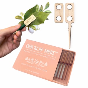 May include: A peach box of Quickclip Minis magnetic boutonniere clips with a floral design. The box is open, revealing several clips. Also shown are wooden clips and a boutonniere with a Quickclip attached.
