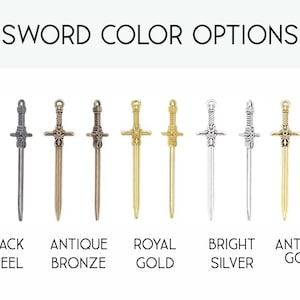 May include: A collection of ten sword charms arranged in pairs, labeled SWORD COLOR OPTIONS. The finishes include black steel, antique bronze, royal gold, bright silver, and antique gold. Each charm features a detailed hilt, crossguard, and blade.