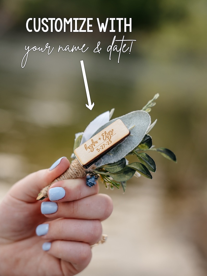 K&ouml;nnte beinhalten: Ein kleines Bouquet aus Gr&uuml;npflanzen mit einem Holzschild, auf dem "Hayden + Elyse 5-27-23" steht.